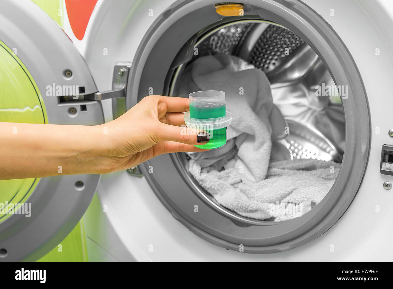 Hand pours liquid powder into the washing machine. Stock Photo