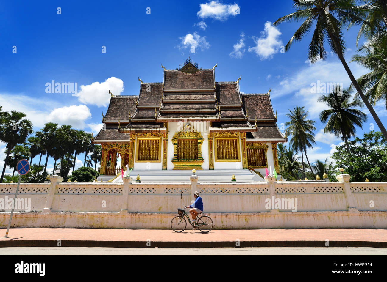 Loungprabang,Laos - August 7,2015: Buddhist Temple at Loungprabang royal palace and unfocus of unidentified woman cycling on the main street of the ci Stock Photo