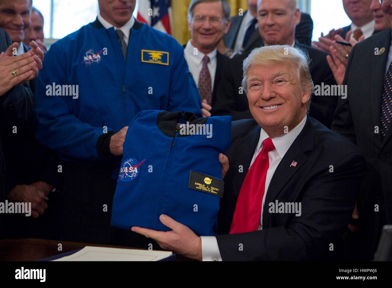 U.S. President Donald Trump smiles as he holds up a NASA flight jacket presented after signing the NASA Transition Authorization Act of 2017 in the Oval Office of the White House March 21, 2017 in Washington, D.C. Stock Photo