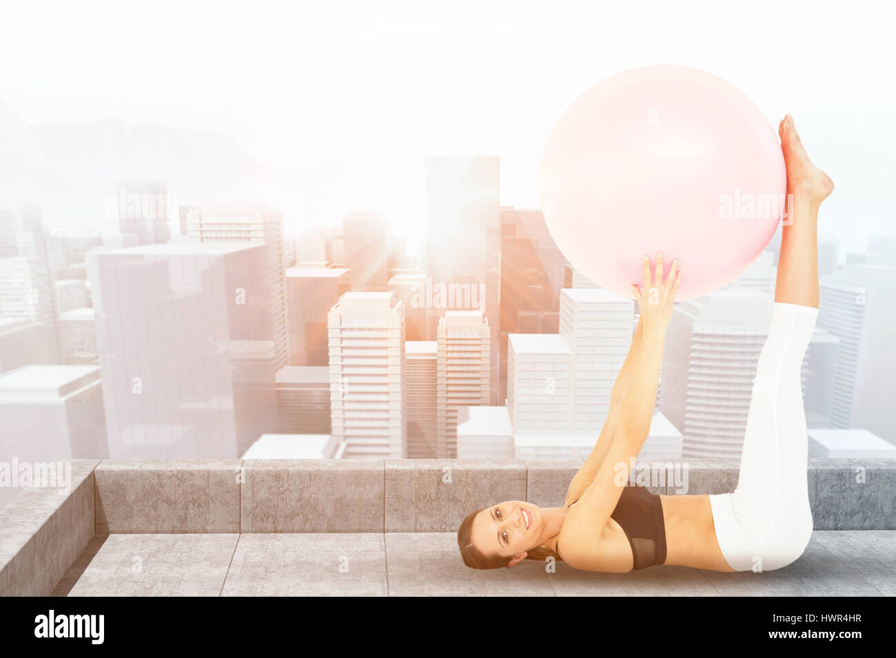 Side view of a fit woman exercising with fitness ball against view from ...