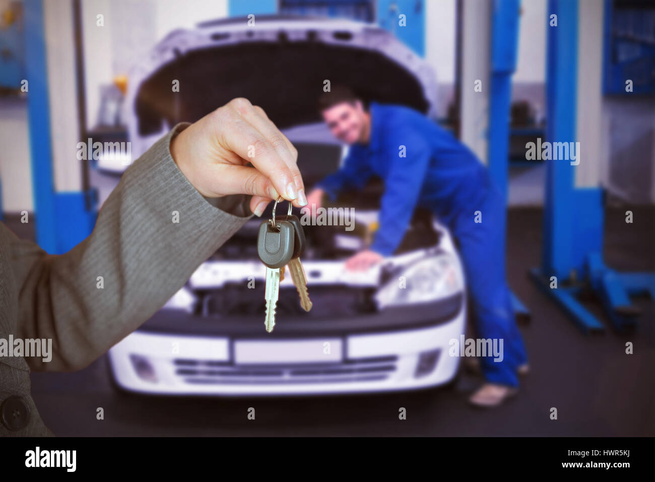 Person handing keys to someone else against mechanic examining under