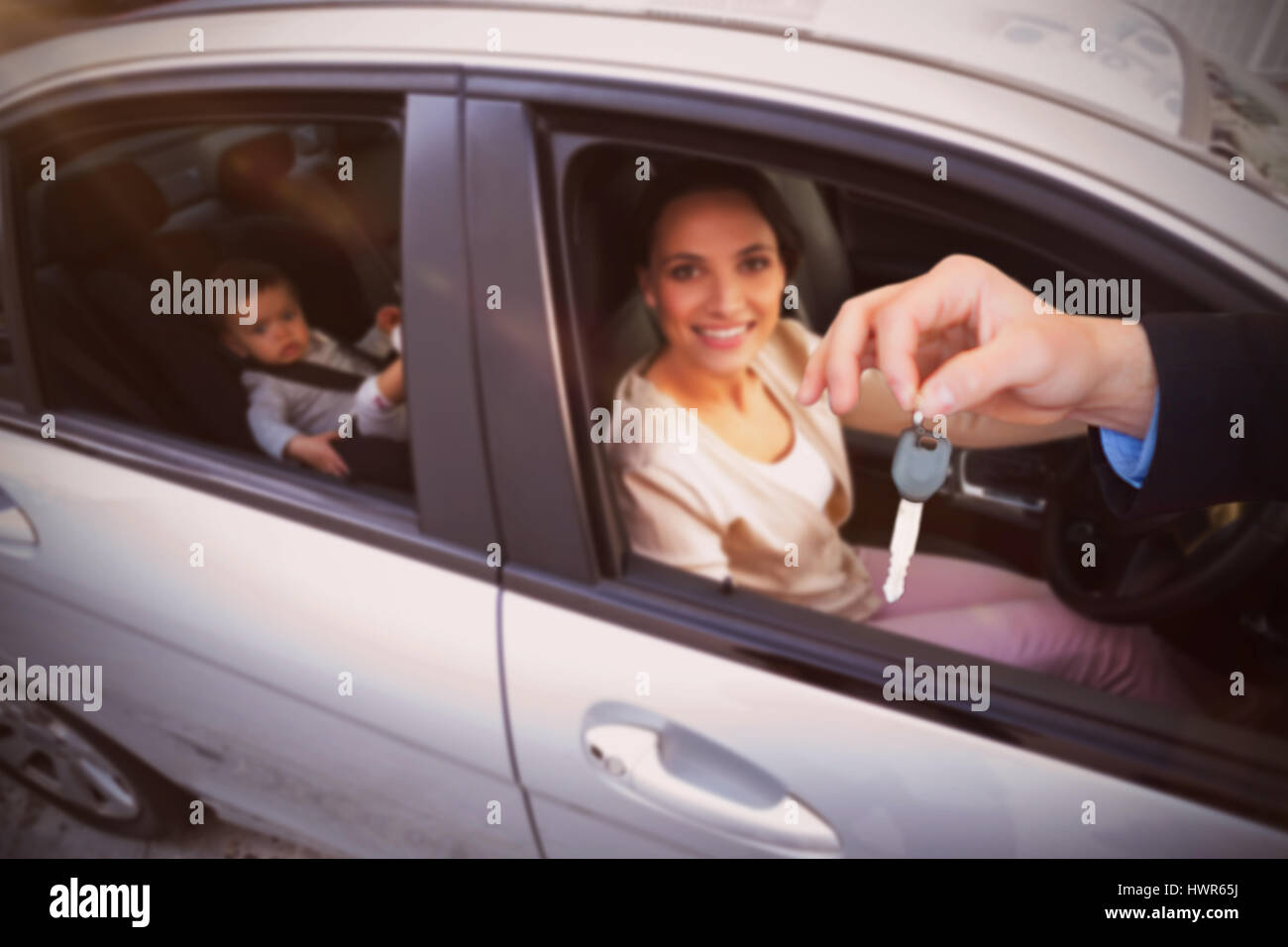 Customer receiving car keys against mother with her baby in the car