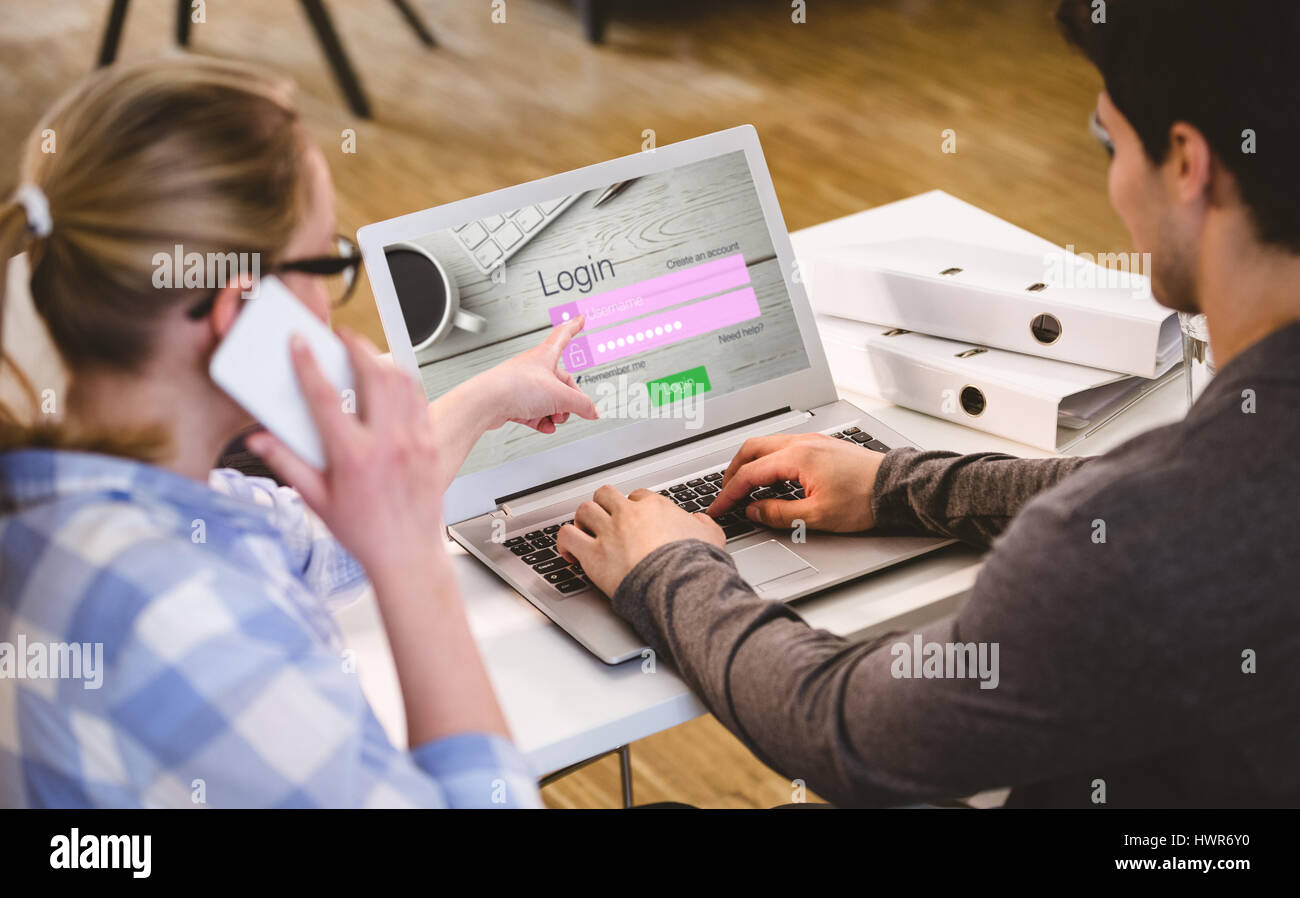 Close-up of login page against rear view of executives working at ...