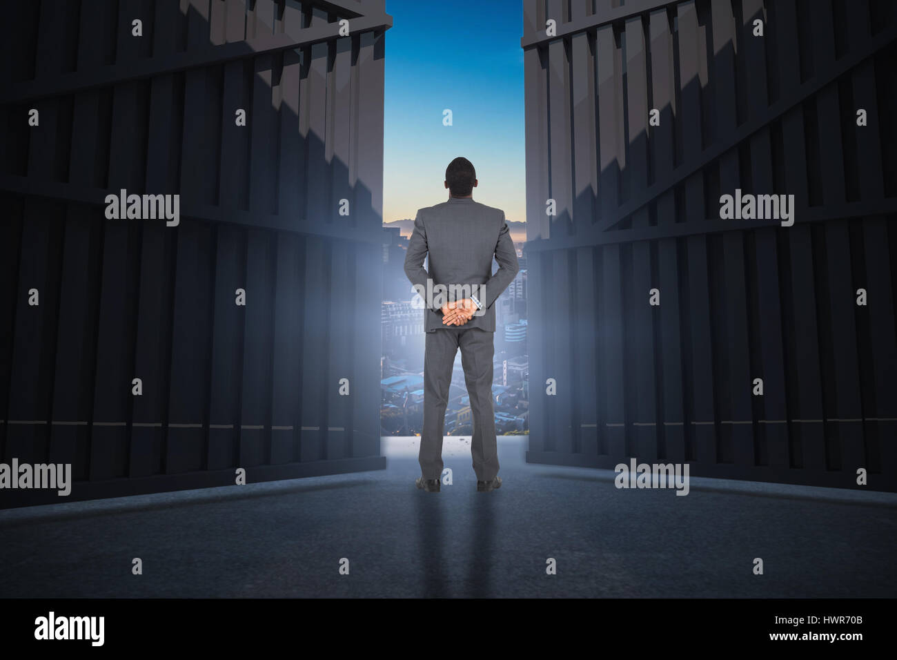 Young businessman standing with hands behind back against beautiful view of city skyline 3d Stock Photo