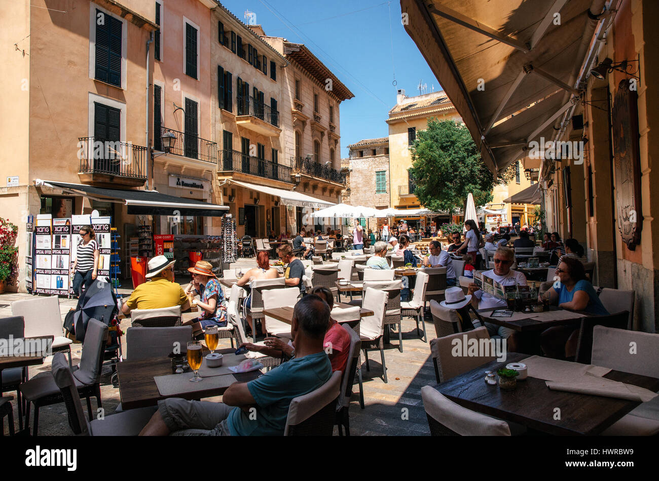 ALCUDIA, MAJORCA, SPAIN - May 23, 2015. Crowded square of Alcudia. People relax and enjoy their drinks and food at an outdoor cafe terrace. Stock Photo