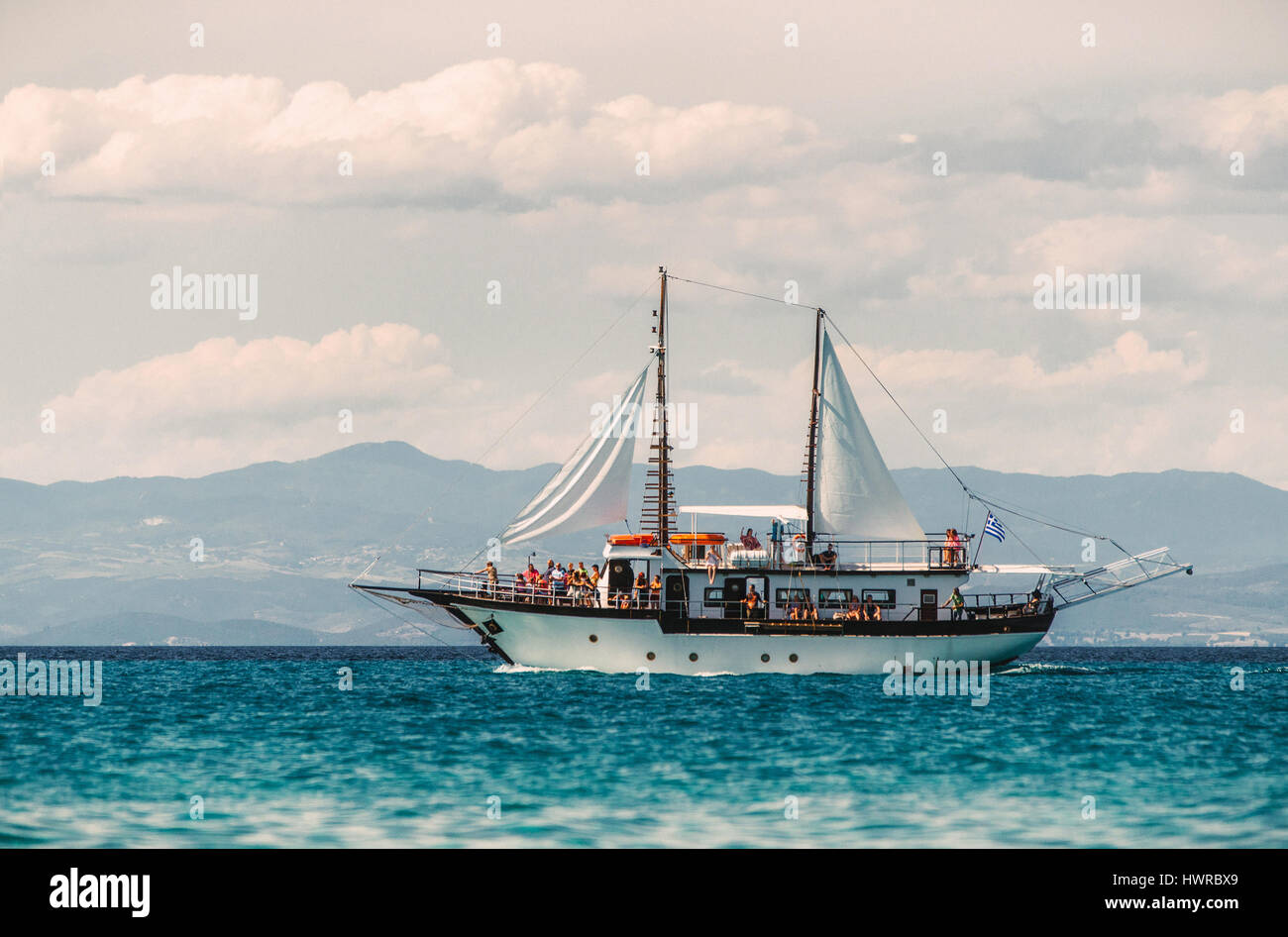 PEFKOHORI, GREECE - MAY 26, 2015: Sailing ship sails in the Aegean Sea on the background of mountains and hills of the peninsula Sithonia, Halkidiki. Stock Photo