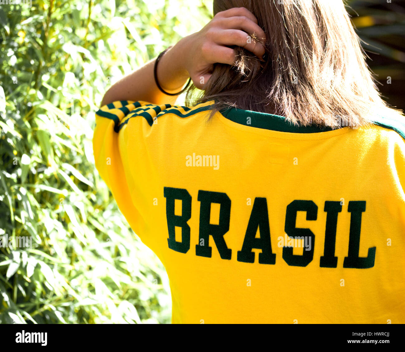 a young girl wearing a sports shirt in the Brasil national colours of green and yellow with Brasil spelt out across the back Stock Photo