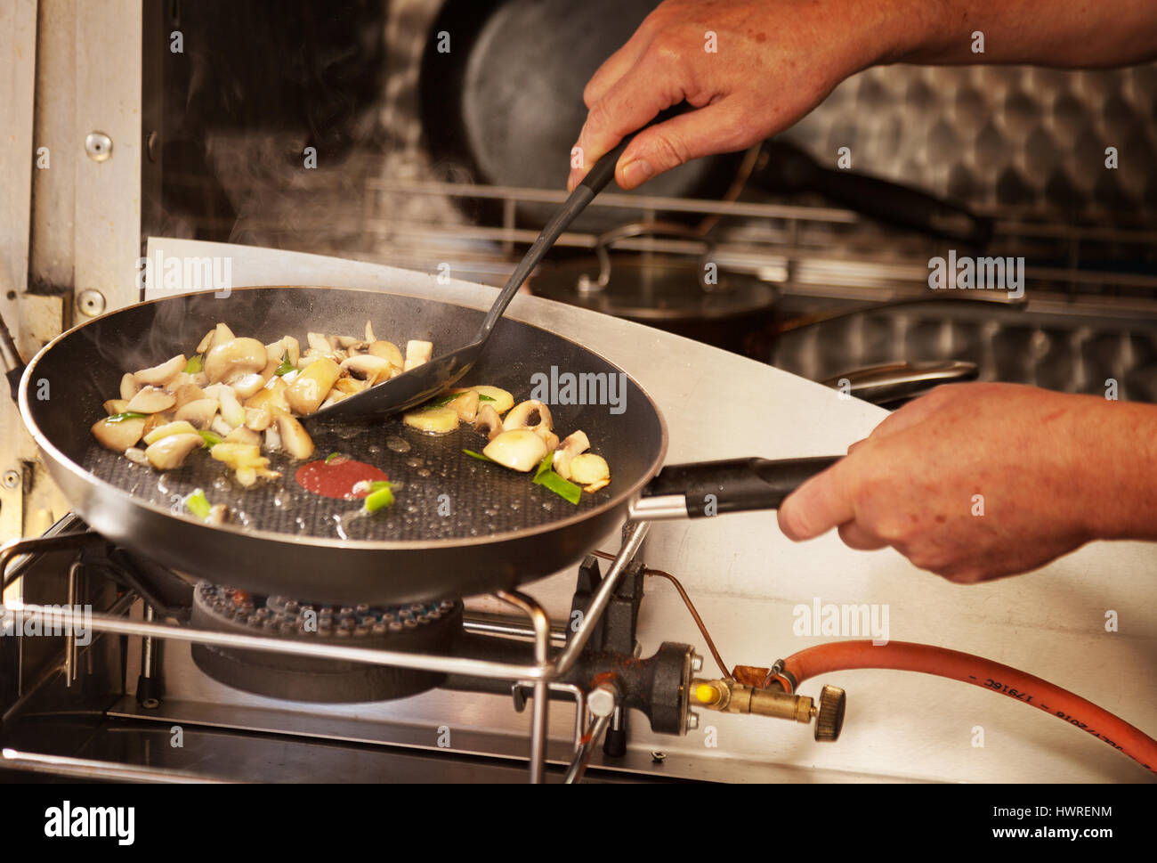 Frying vegetables in a frying pan on a calor gas stove, UK Stock Photo