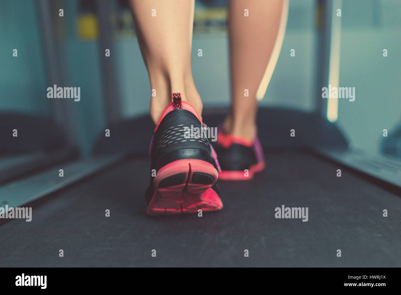 Female muscular feet in sneakers running on the treadmill at the gym. Concept for fitness, exercising and healthy lifestyle Stock Photo