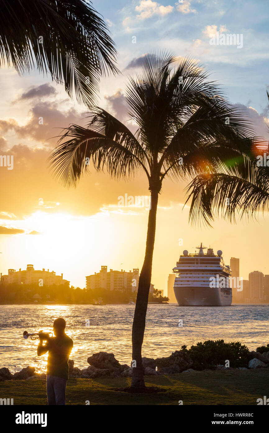 Miami Beach Florida,South Pointe Park,public park,Government Cut,water,cruise ship,departing port,sunset,palm tree,man men male,horn,trumpet player,mu Stock Photo