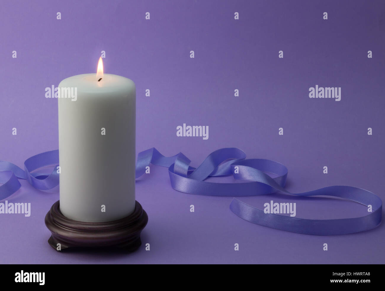 White lit candle with lilac ribbon and background Stock Photo Alamy
