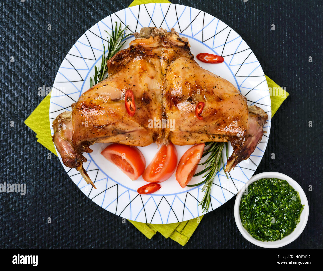 Baked rabbit legs on a plate on a black background. The top view Stock ...