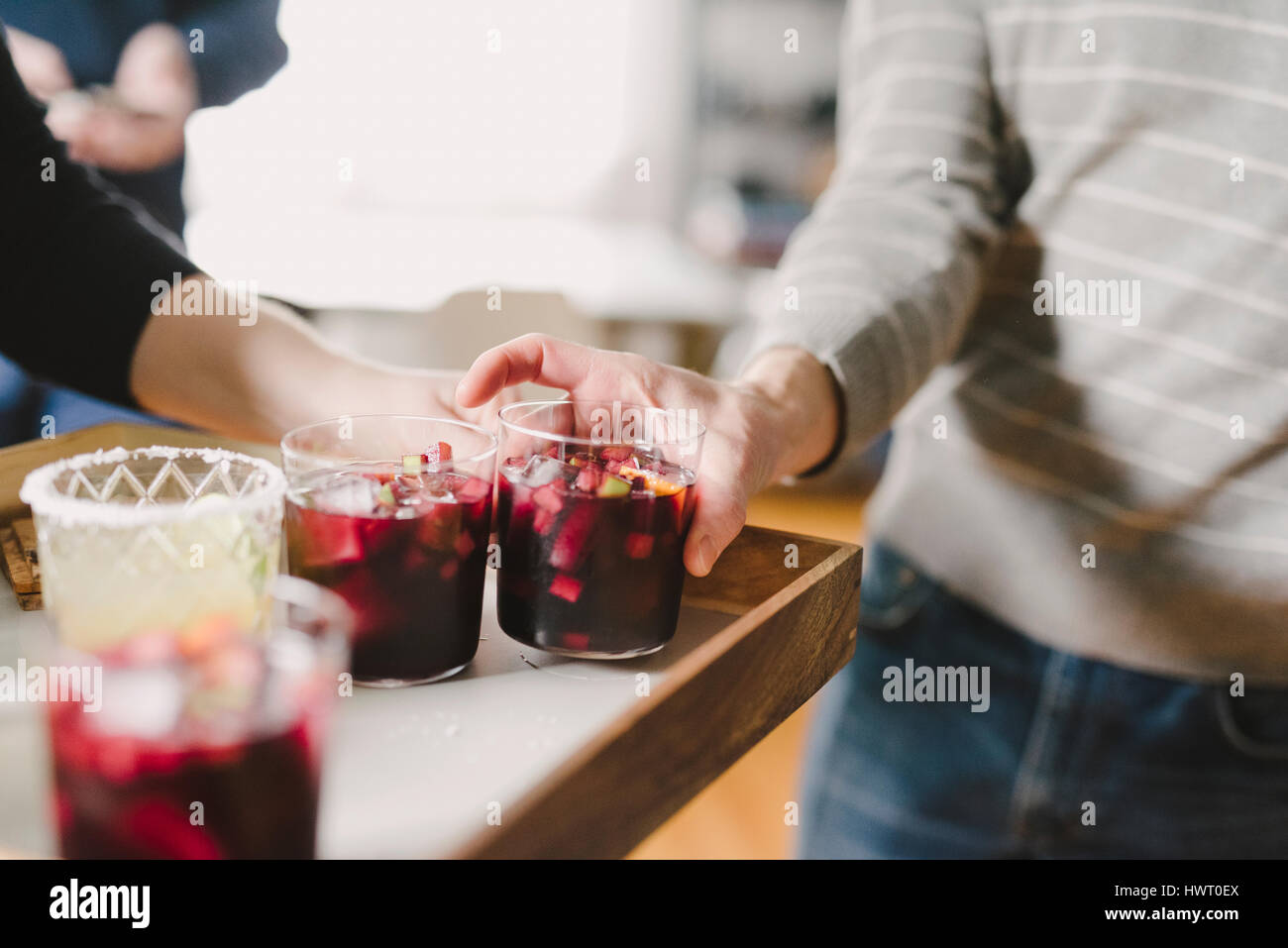 Cropped hand of woman serving drinks to male friend in party at home