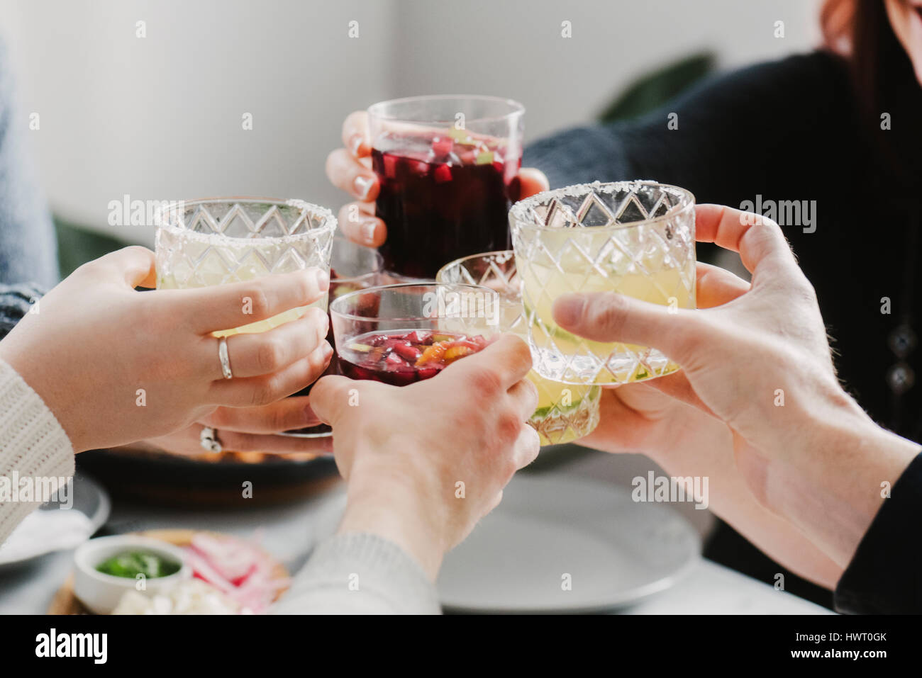 Cropped hands of friends toasting drinks in party at home Stock Photo