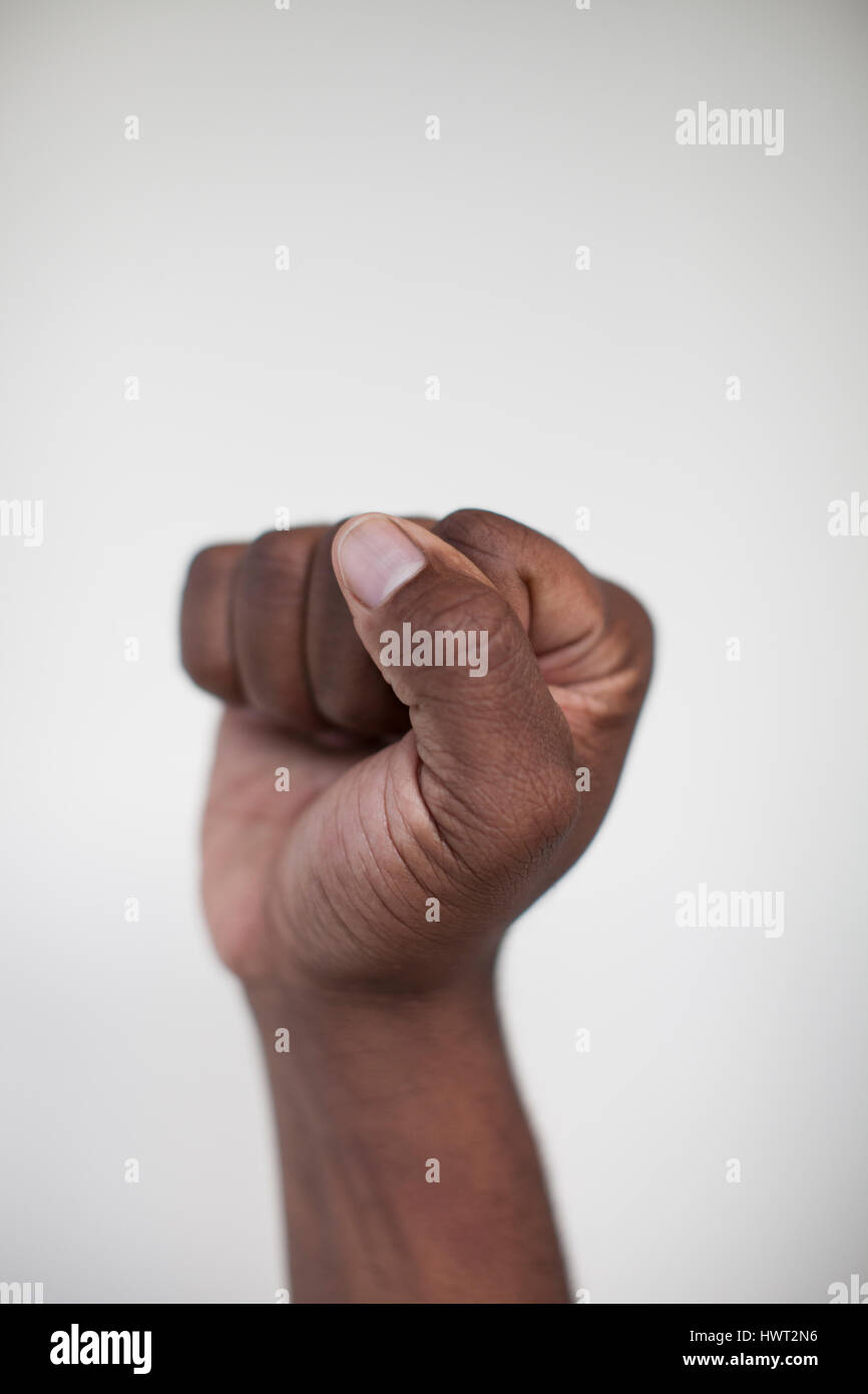 Cropped hand of man clenching fist against white wall at home Stock Photo