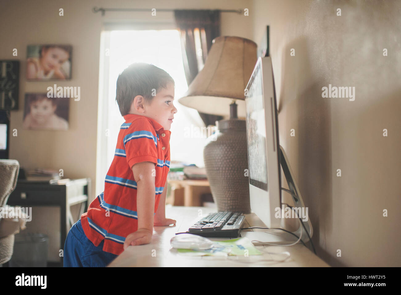 Boy looking at desktop computer while standing by table at home Stock Photo