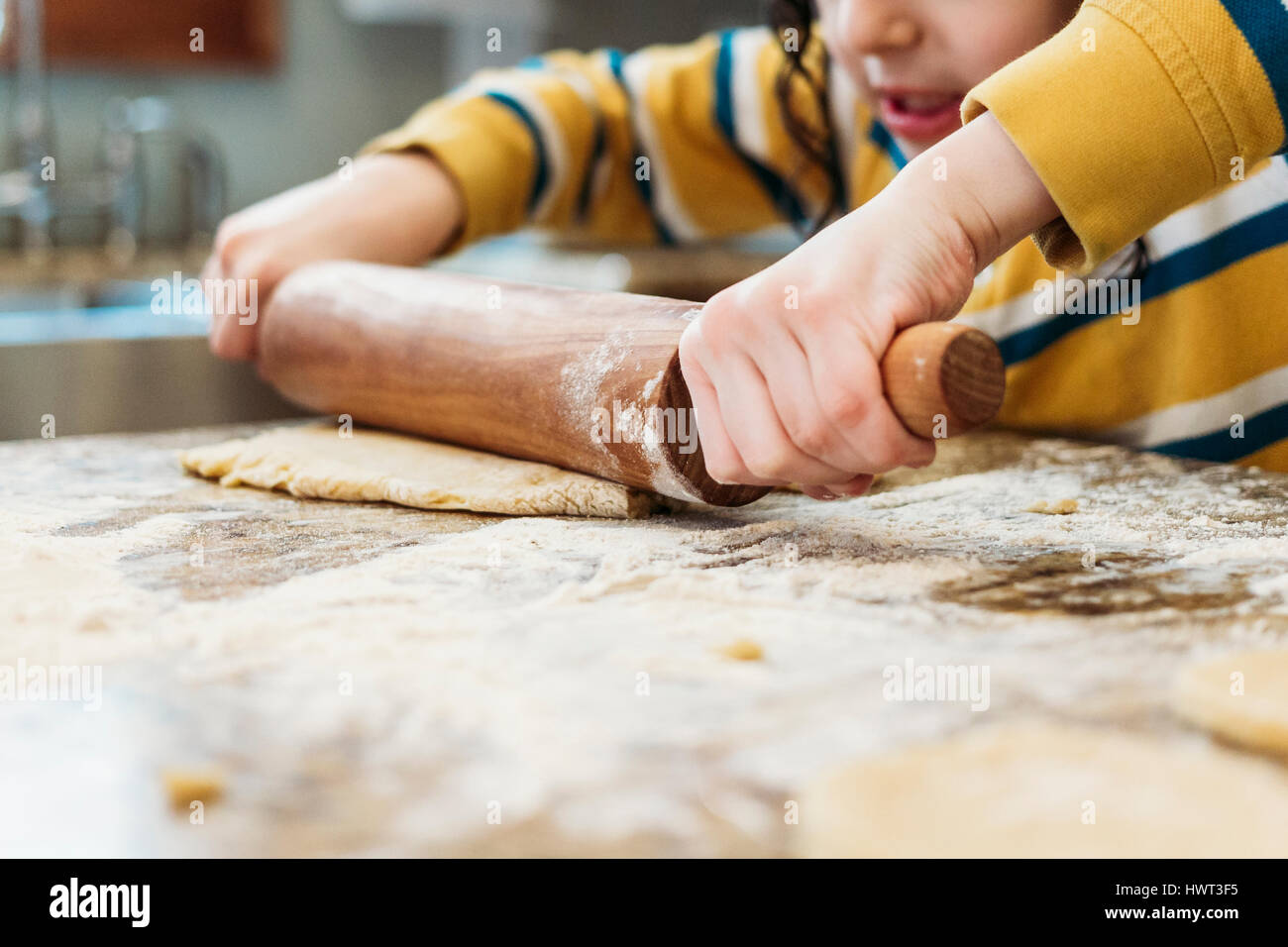 Midsection of boy rolling dough in kitchen at home Stock Photo