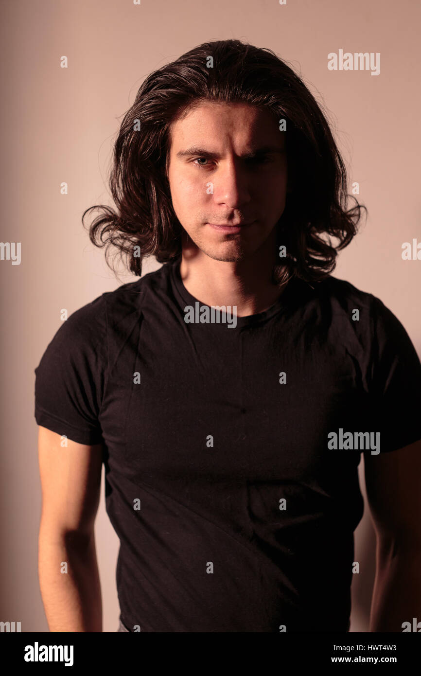 Brutal man in black with long hair. Stock Photo