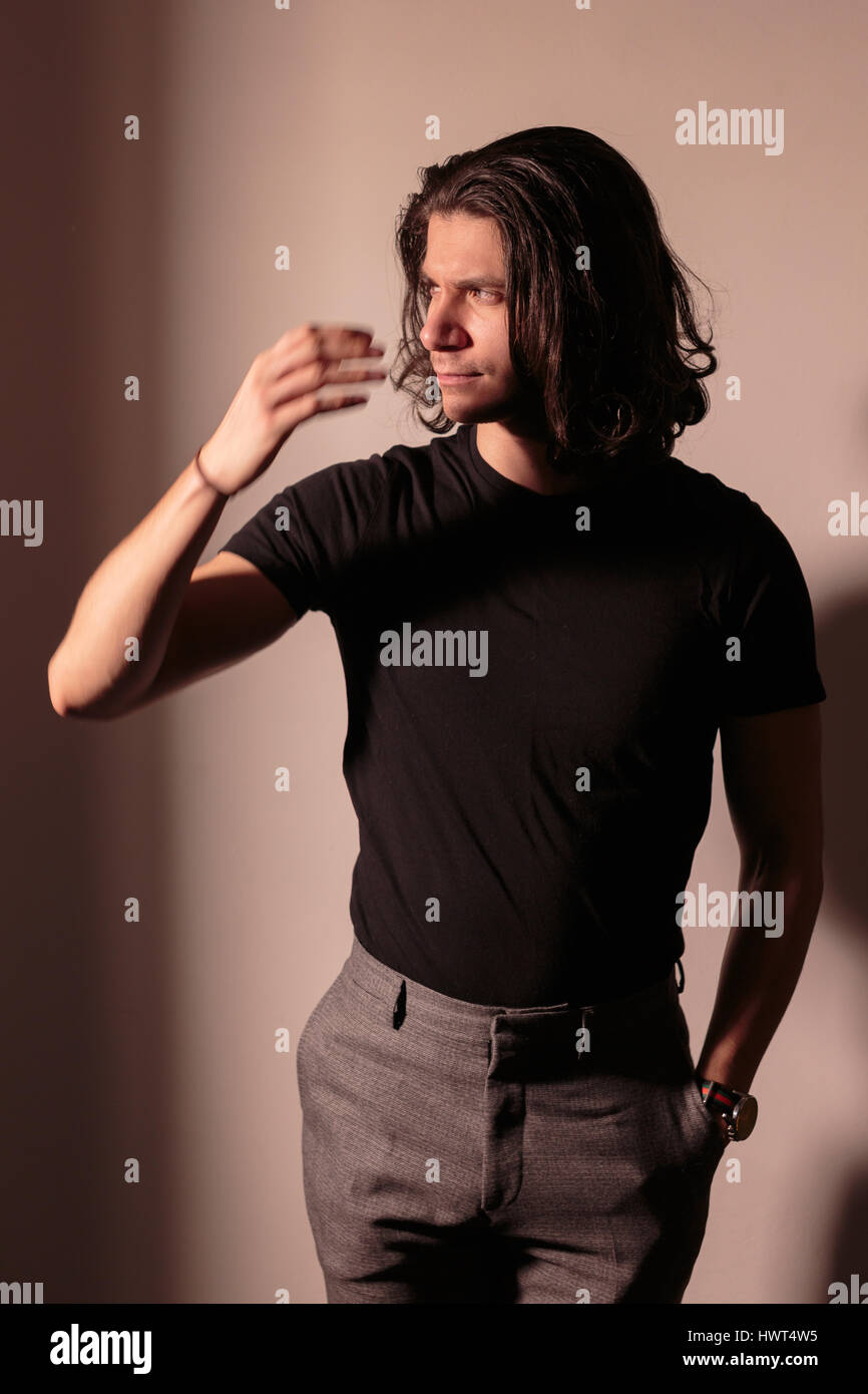 Brutal man in black with long hair. Stock Photo