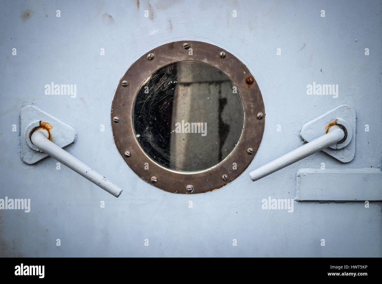 Close-up of a porthole and two levers in the grey door of a ship Stock Photo