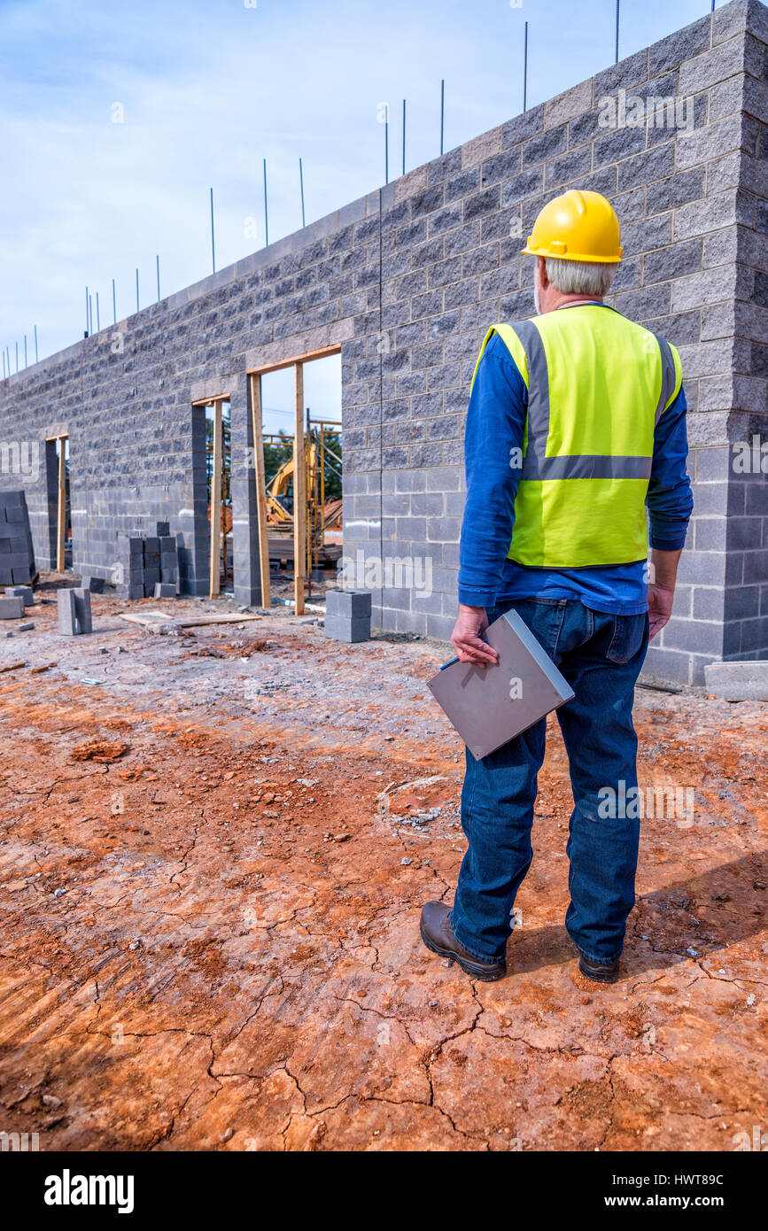 A gray-haired construction supervisor inspects a new retail building job. Stock Photo
