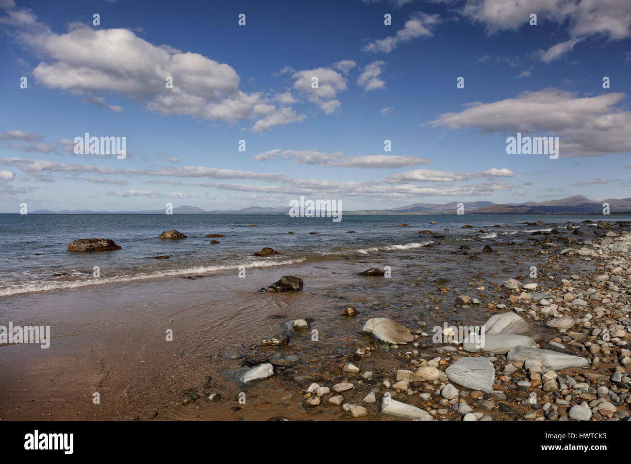 Deserted rocky beach on the coast of Snowdonia near Harlech with views to the distant mountains Stock Photo