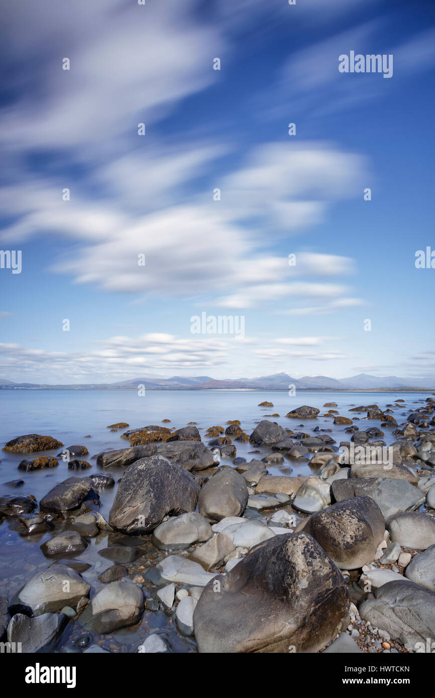 Long exposure image of clouds and shoreline on a rocky beach near Harlech in North Wales Stock Photo