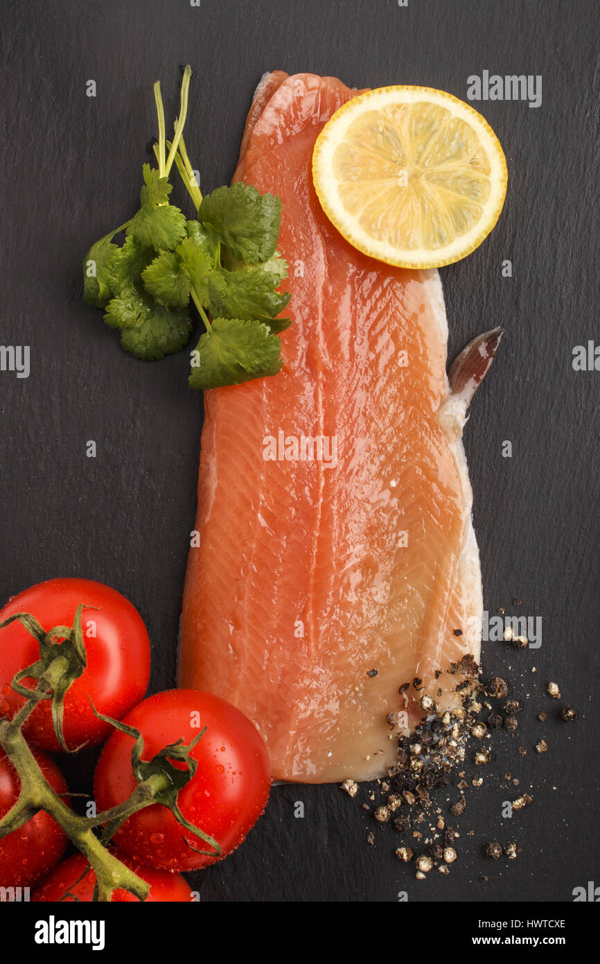 raw trout fillet with slice lemon, wet tomato crushed peppercorn and