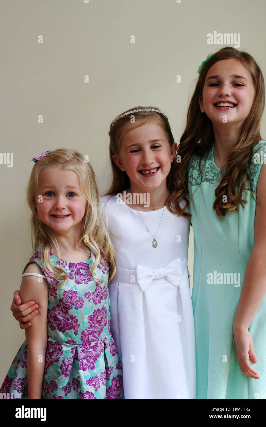 Three girls having fun together First Holy Communion Day happy kids great joy laughter family sisters celebration together connection laugh out loud Stock Photo