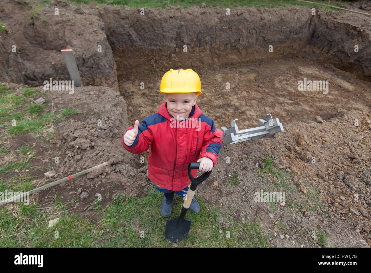 Little boy with a spade helps parents during the construction of the ...