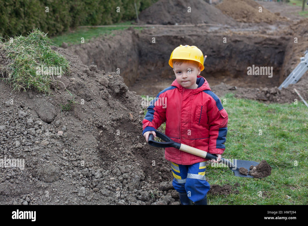 Little boy with a spade helps parents during the construction of the ...