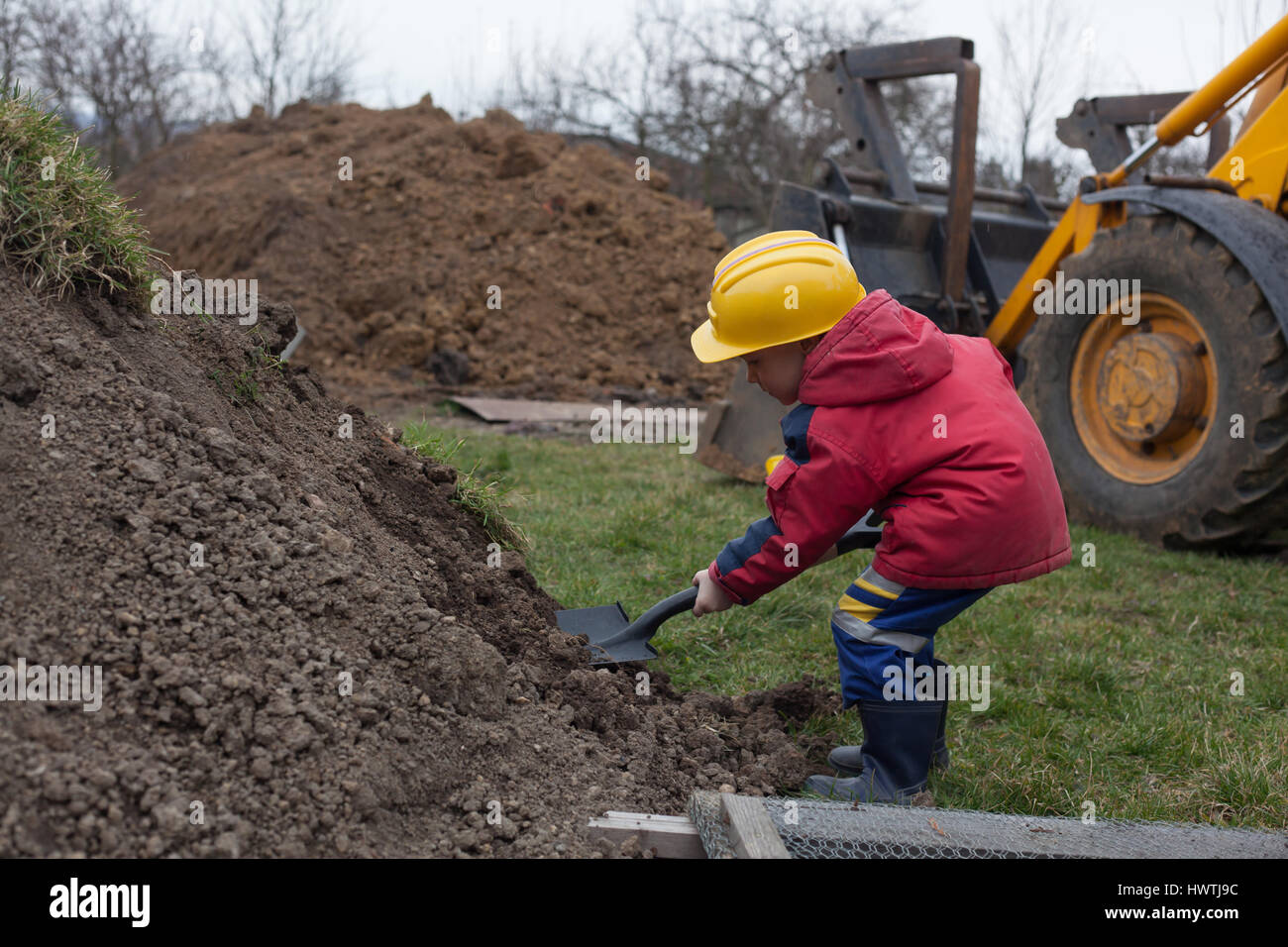 Little boy with a spade helps parents during the construction of the ...