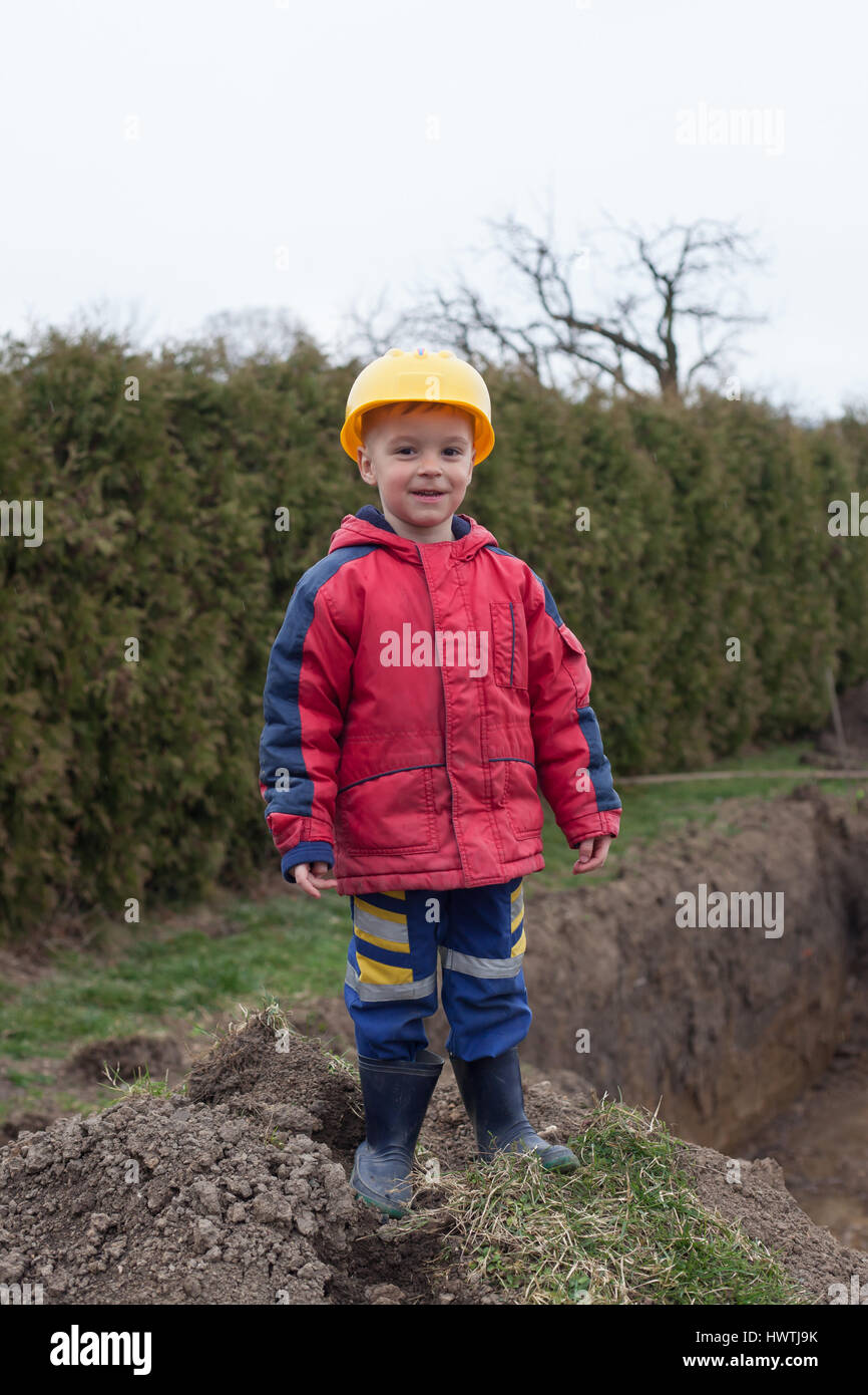 Little boy with a spade helps parents during the construction of the ...