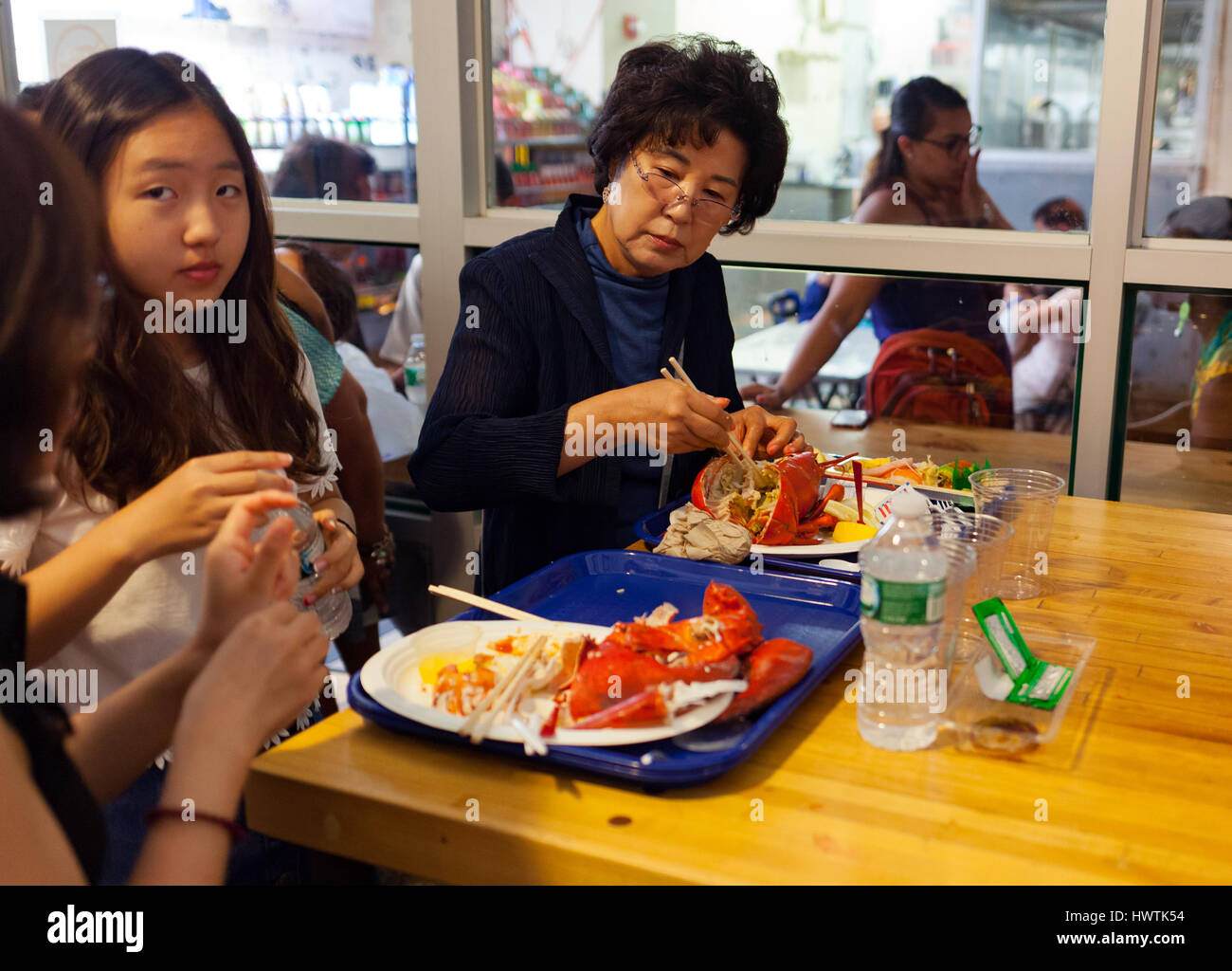 New York City, Usa - July 12, 2015: Asian tourists eating fresh lobsters in Chelsea Market. The market has a number of eateries and food outlets. Stock Photo