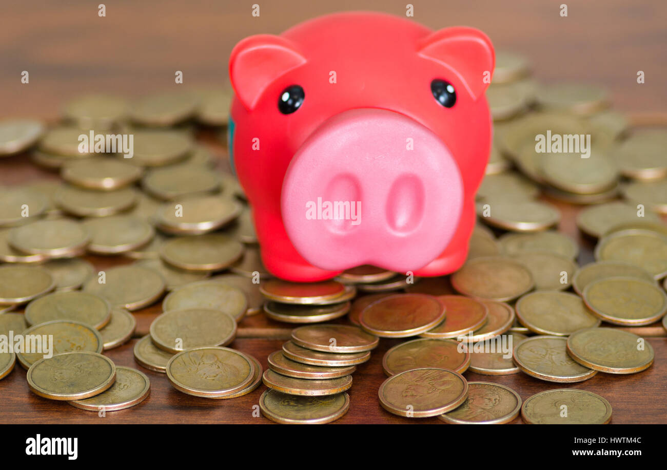 Pink piggy bank sitting on top of coins spread out in pile Stock Photo ...