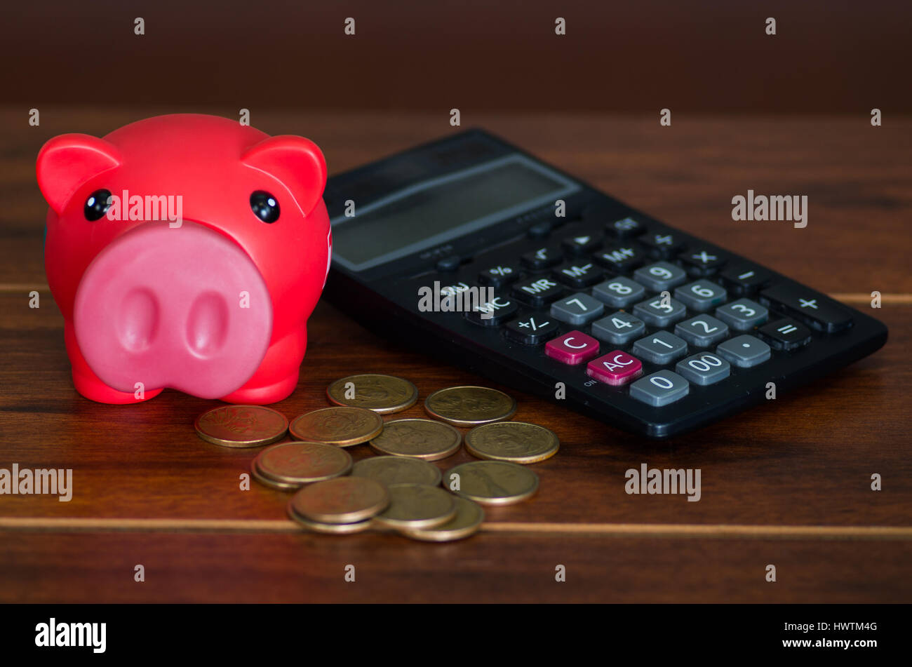 Pink piggy bank sitting on pile of coins next to calculator Stock Photo ...