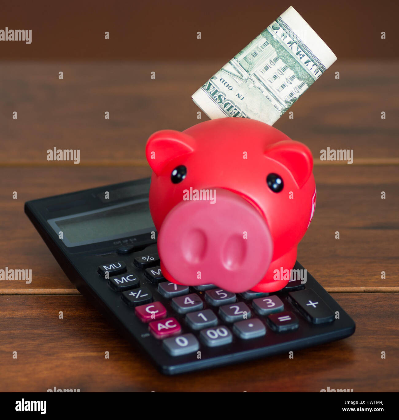 Pink piggy bank sitting on top of calculator, twenty dollar bill ...