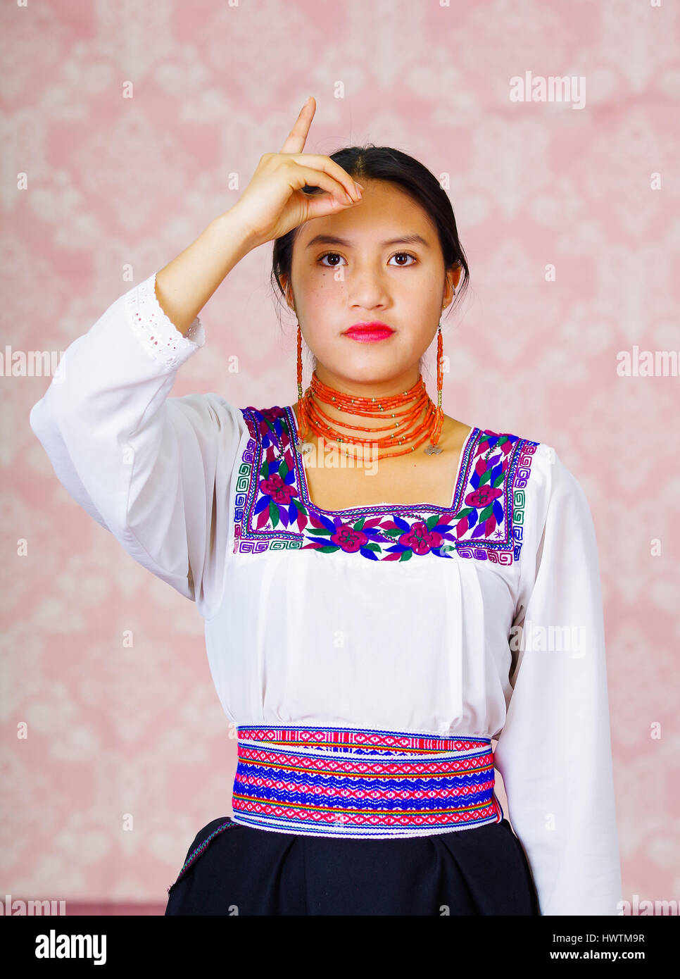 young-woman-wearing-traditional-andean-dress-facing-camera-doing-sign