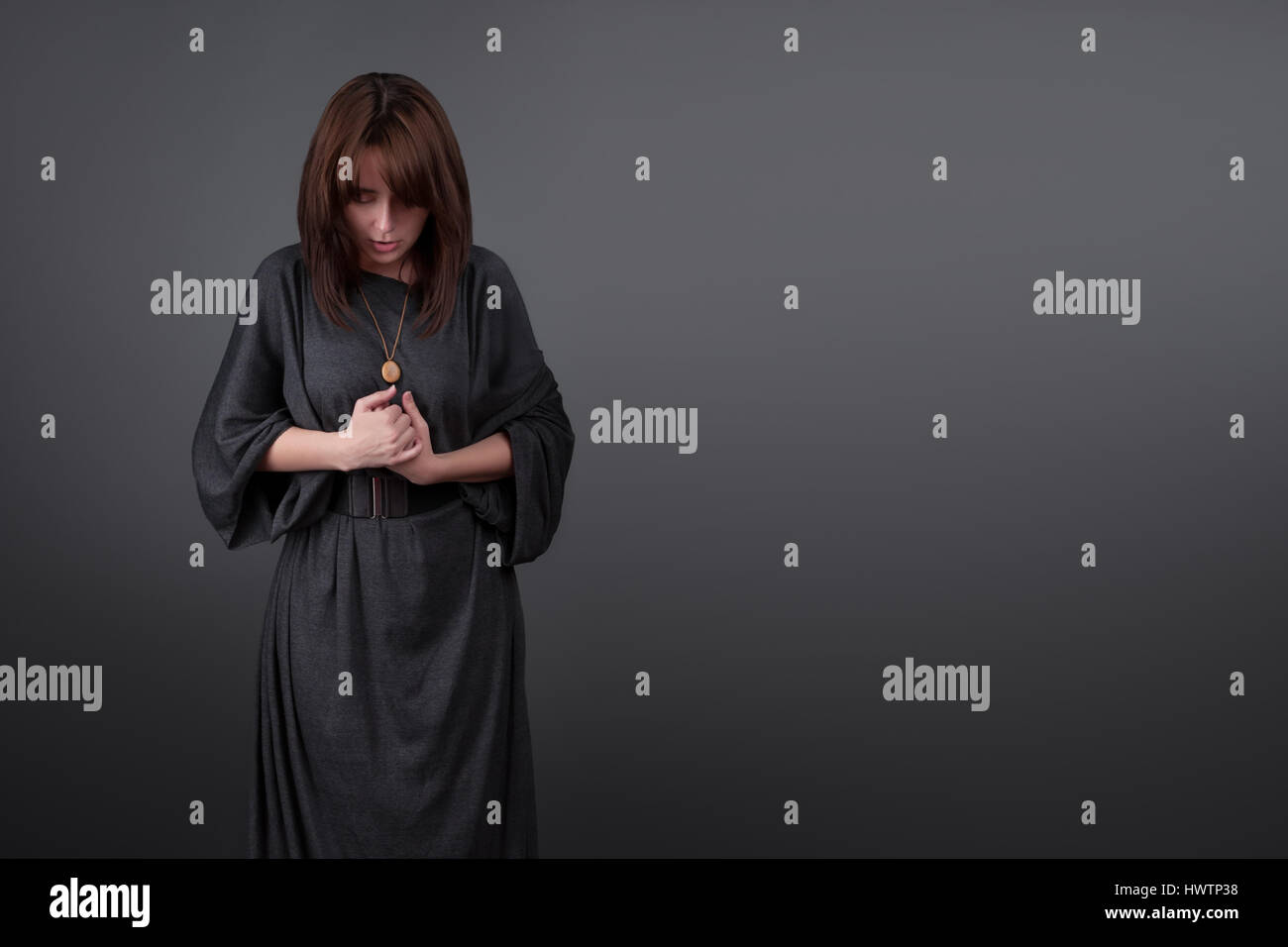 Portrait of a young caucasian woman praying. Prayer girl dressed in Vestments of a nun on gray studio background. Religion and hope concept Stock Photo