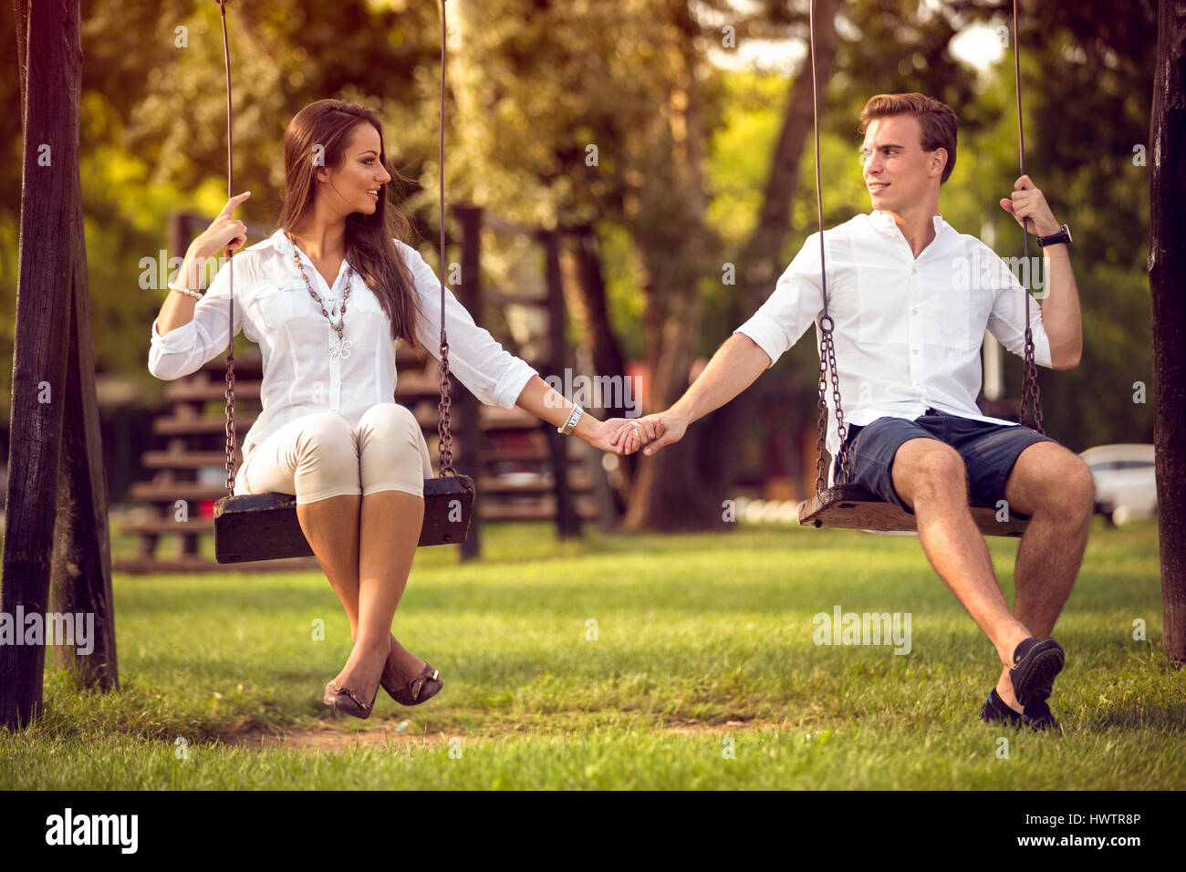young modern stylish couple playing swings outdoor Stock Photo