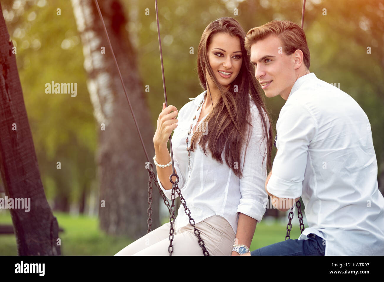 Young couple in love on swings, outdoor Stock Photo