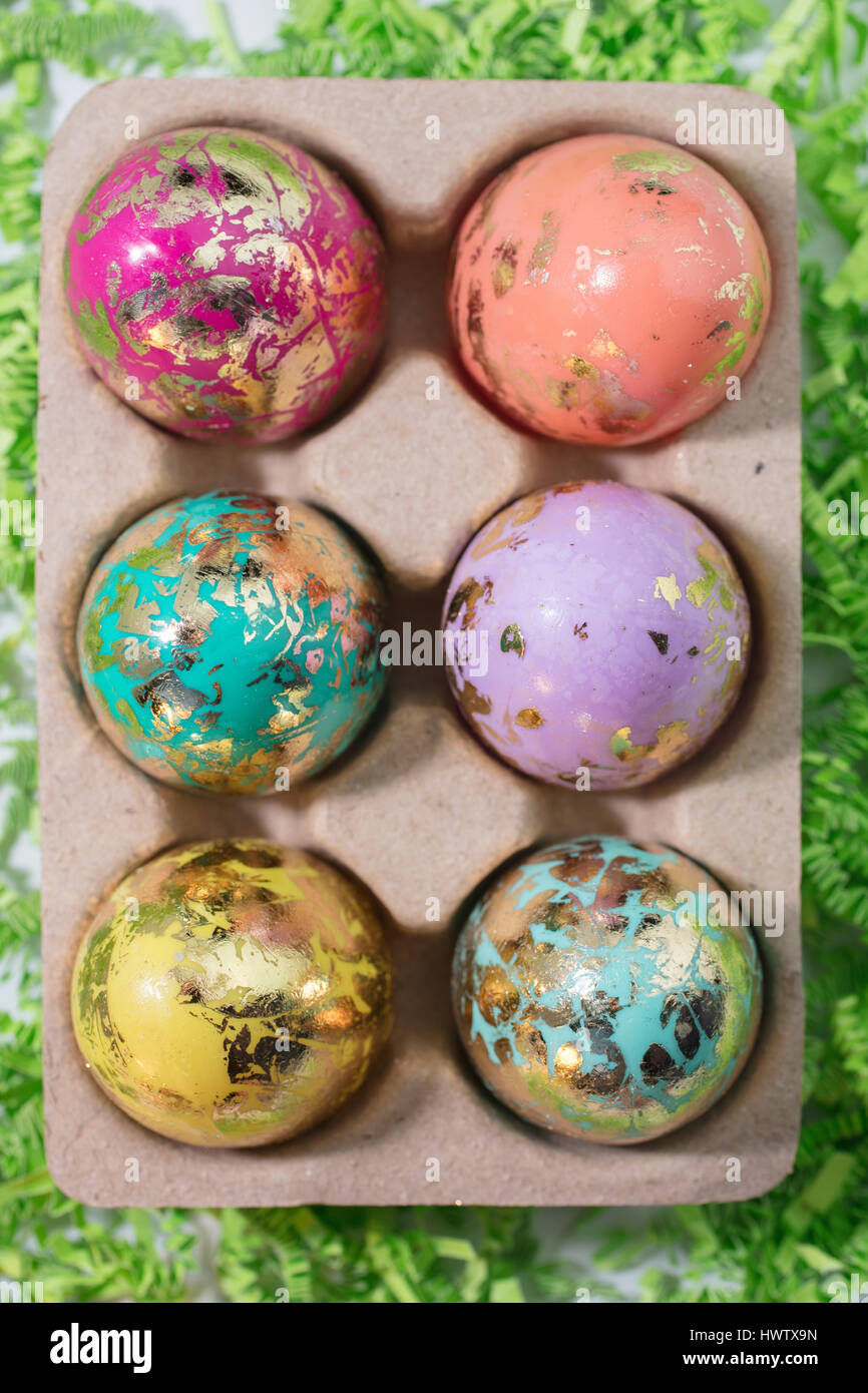 Foiled and Colorful Easter Eggs in Pink, Aqua, Yellow, Orange and Gold, in an egg container Stock Photo