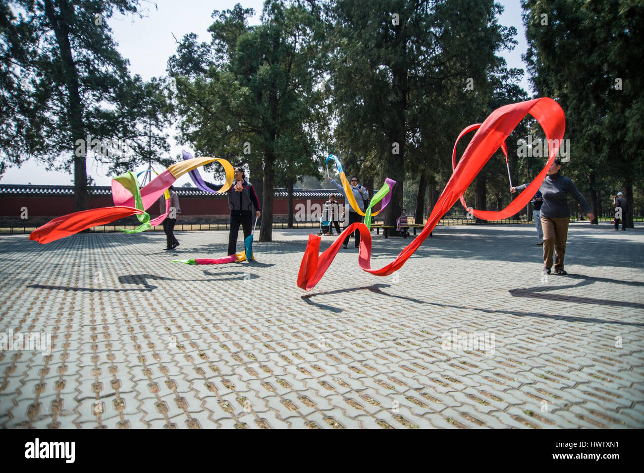 Chinese women dancing with long and colorful silk ribbons in the Temple of Heaven park in Beijing, China.  Horizontal low angle Stock Photo