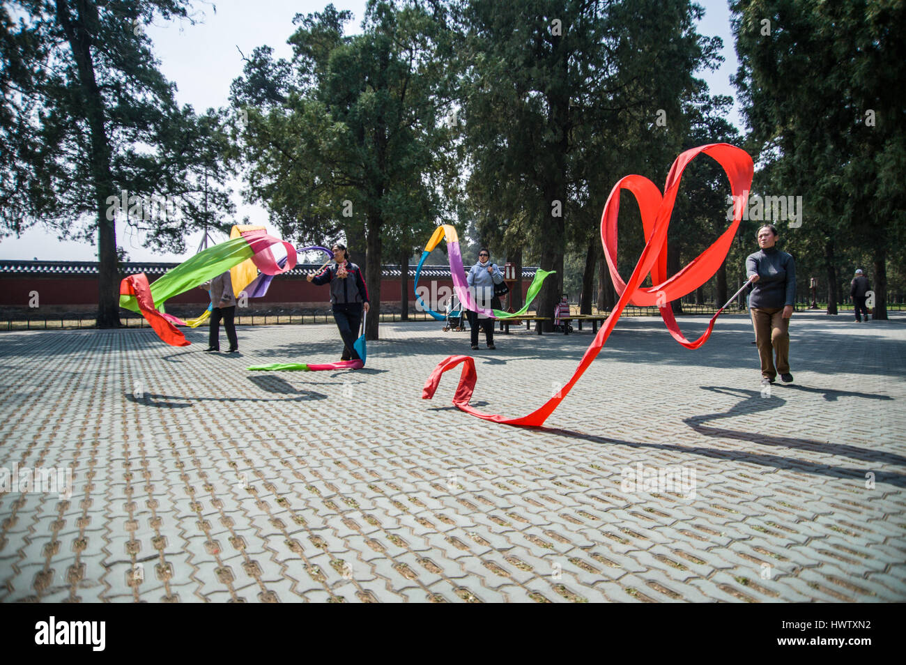 Chinese women dancing with long and colorful silk ribbons in the Temple of Heaven park in Beijing, China.  Horizontal low angle Stock Photo