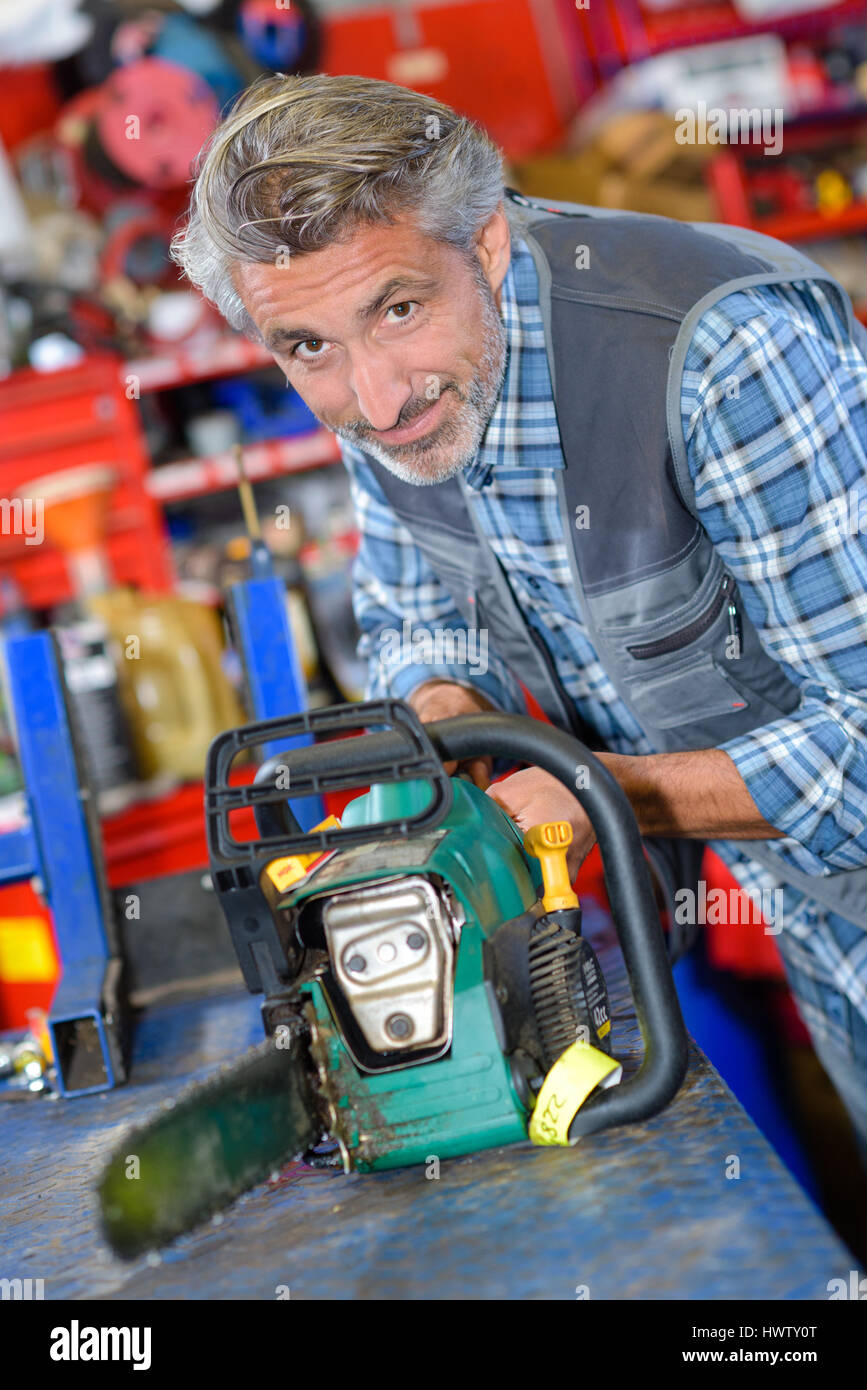 Portrait of mechanic working on chainsaw Stock Photo