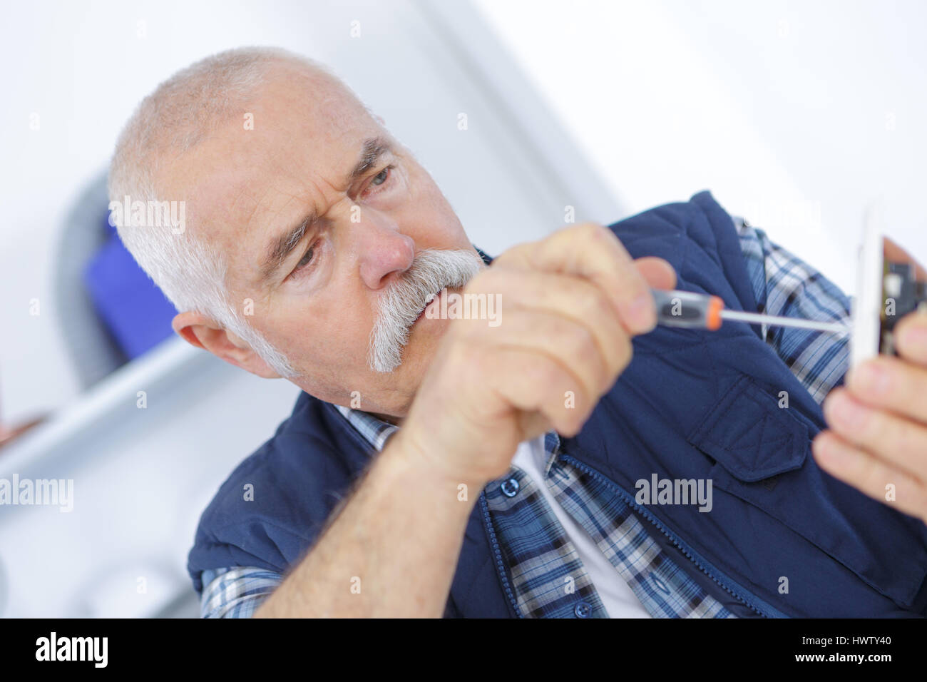 senior adult electrician checking and repairing plug Stock Photo
