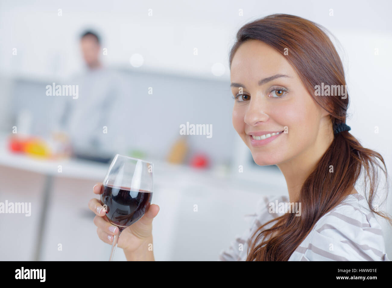 Lady holding glass of wine, partner in background Stock Photo - Alamy