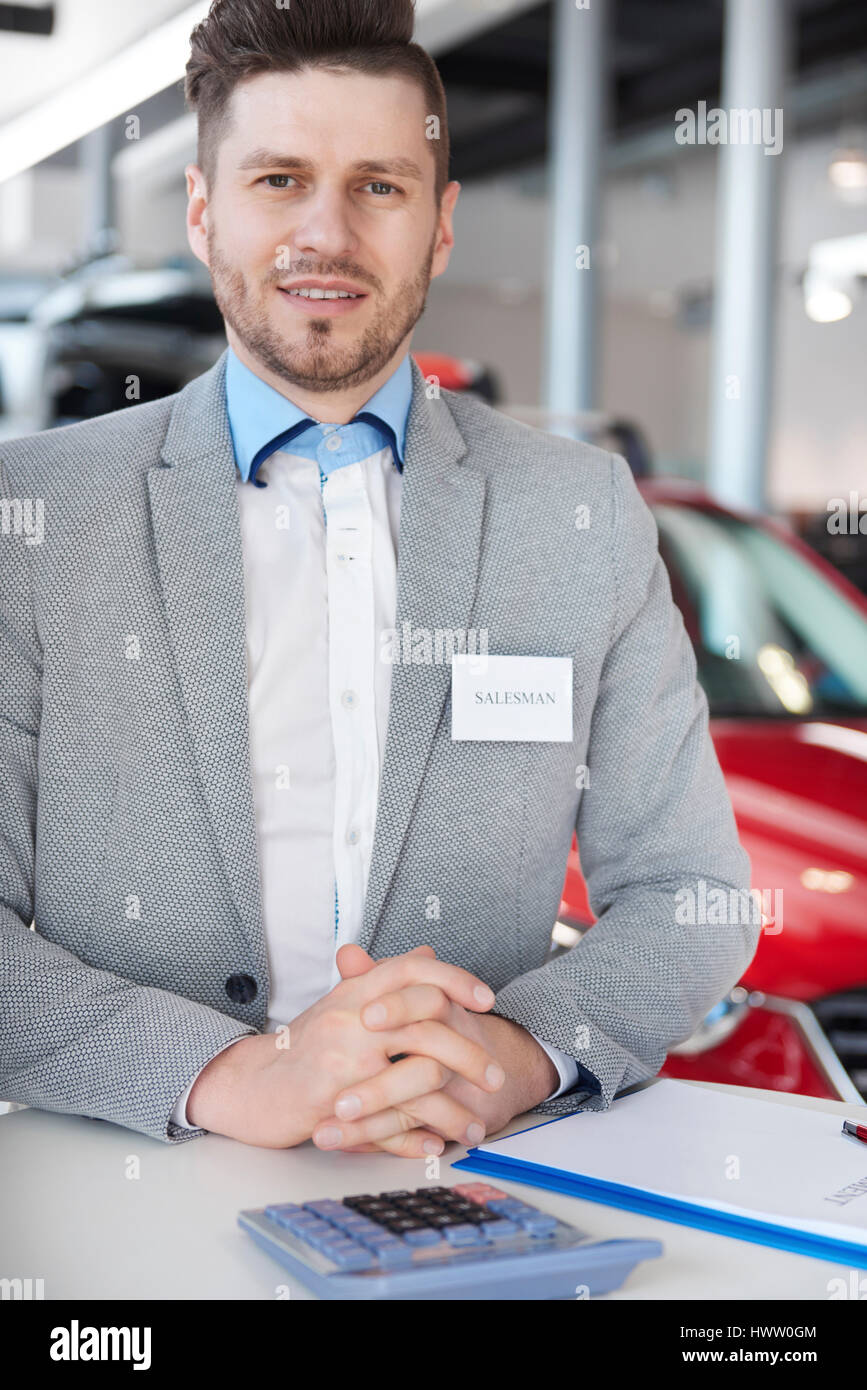 Car salesman standing in automobile showroom Stock Photo