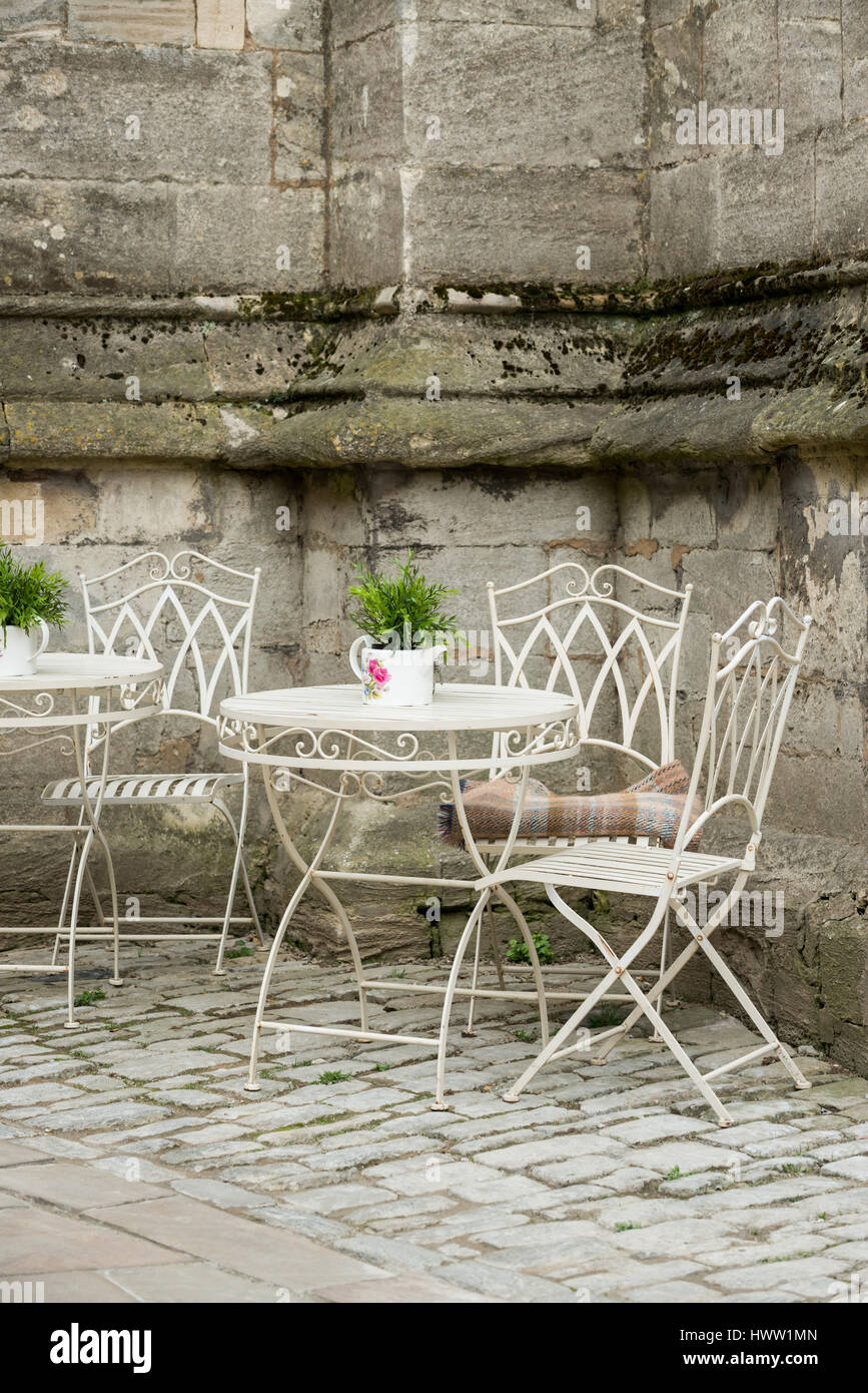 Ornate metal table and chairs outside St John the Baptist parish church ,Cirencester in the Cotswolds, Gloucester, England, UK Stock Photo