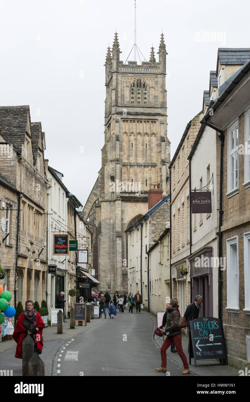 People walk down Black Jack Street with St John the Baptist parish church in the distance, Cirencester in the Cotswolds, Gloucester, England, UK Stock Photo